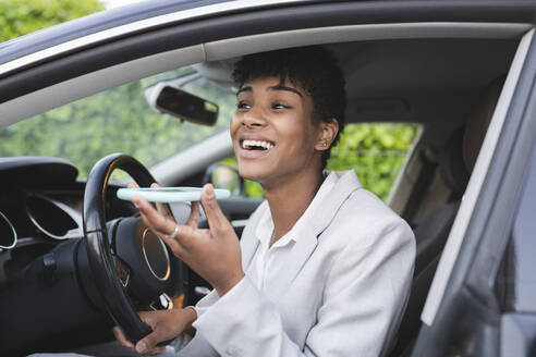 Geschäftsfrau sendet Sprachnachrichten über ihr Smartphone, während sie im Auto sitzt - JCCMF02951