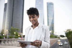 Smiling businesswoman using digital tablet in city - JCCMF02955