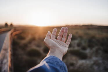 Frau zeigt Handfläche bei Sonnenuntergang - EBBF04090