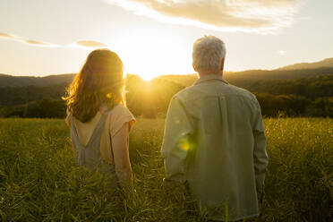 Vater und Tochter stehen bei Sonnenuntergang auf einem Feld - AFVF09017