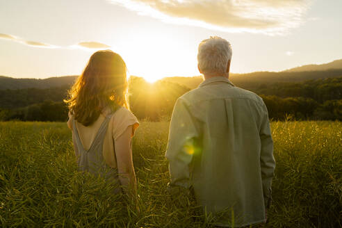 Father and daughter standing in field during sunset - AFVF09017