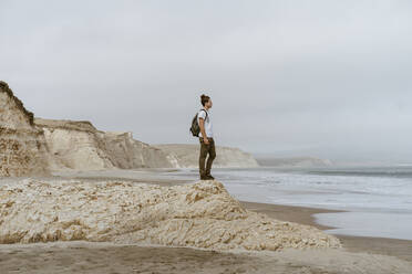 Man standing on rock at beach in Point Reyes, California, USA - AFVF09026