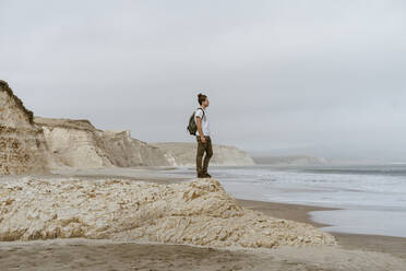 Mann steht auf einem Felsen am Strand von Point Reyes, Kalifornien, USA - AFVF09026