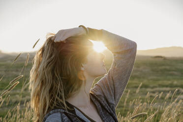 Woman with head in hand at agricultural field during sunset - AFVF09031