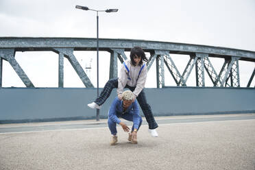 Lesbisches Paar, das auf einer Brücke Bocksprung spielt - PMF01872
