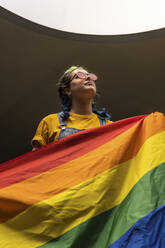 Frau mit Sonnenbrille und Regenbogenflagge in der Hand - MGRF00303