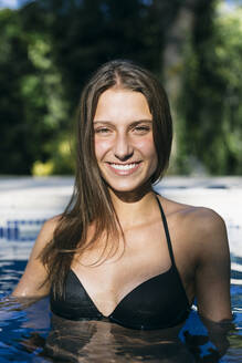Lächelnde junge Frau im Schwimmbad während der Ferien - ABZF03590