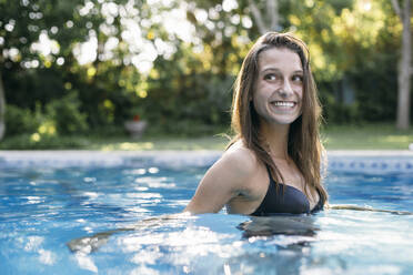 Lächelnde Frau mit braunem Haar im Schwimmbad schaut weg - ABZF03592