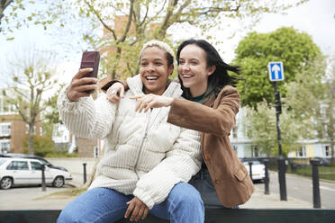 Glückliches lesbisches Paar nimmt Selfie zusammen durch Smartphone - PMF01894