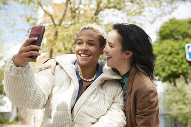 Glückliches lesbisches Paar nimmt Selfie durch Smartphone - PMF01898