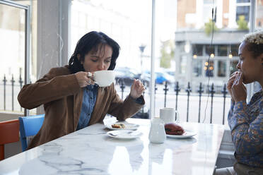 Junge Frau trinkt Kaffee und sitzt mit ihrer Freundin im Cafe - PMF01924