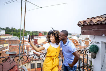 Lächelnder Mann und Frau nehmen Selfie durch Smartphone in Balkon - OCMF02153