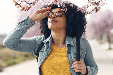 Frau mit Jeansjacke riecht an Kirschblüten - JSRF01553