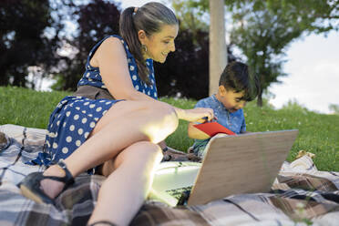 Grandmother telling story to grandson in park during sunset - JCCMF02974