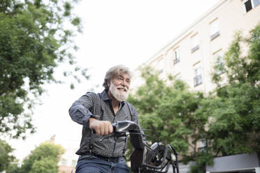 Happy mature  man riding electric bicycle in city - JCCMF03005