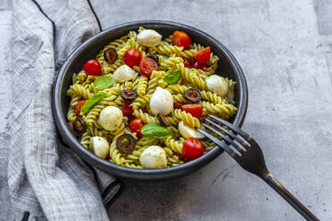 Schüssel mit verzehrfertigem Nudelsalat mit Kirschtomaten, Oliven, Mozzarellakäse und Basilikum - SARF04659