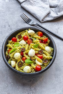 Schüssel mit verzehrfertigem Nudelsalat mit Kirschtomaten, Oliven, Mozzarellakäse und Basilikum - SARF04660