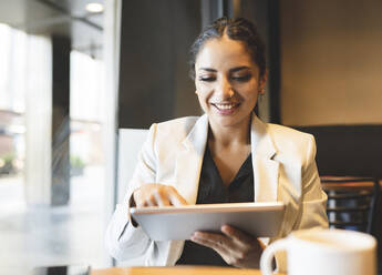 Berufstätige Frau benutzt digitales Tablet in einem Café - JCCMF03038