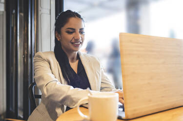 Berufstätige Frau benutzt Laptop bei der Arbeit in einem Cafe - JCCMF03041