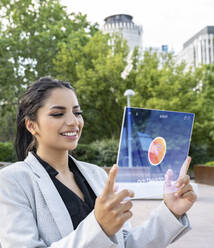 Smiling businesswoman connecting futuristic digital tablet with wifi - JCCMF03083