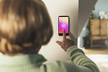 Woman using futuristic home automation device on wall - UUF23652