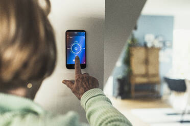 Woman touching home automation device on wall - UUF23653