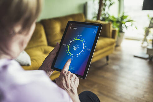 Frau stellt Zeitschaltuhr auf digitalem Tablet zu Hause ein - UUF23669