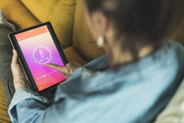 Woman checking room temperature through digital tablet at home - UUF23700