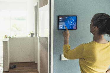 Woman operating home automation device on wall - UUF23713