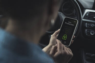 Woman unlocking data protection lock on smart phone in car - UUF23728