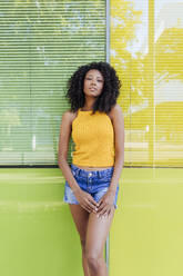 Junge Frau steht vor einem grün-gelben Fenster - JRVF01150