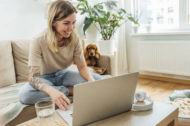 Lächelnde junge Freiberuflerin mit Laptop im Wohnzimmer - VPIF04175