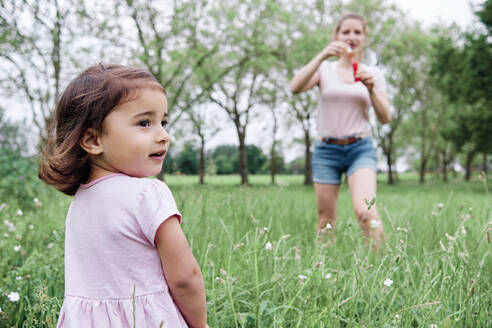 Tochter schaut weg, während Mutter im Park auf dem Rasen steht - ASGF00695