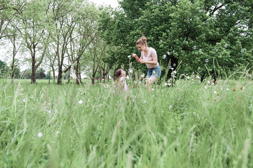 Mutter und Tochter spielen auf dem Rasen im Park - ASGF00696
