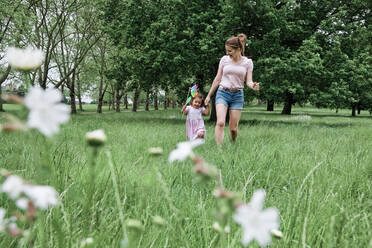 Girl holding pinwheel while walking with mother at park - ASGF00699