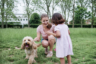 Mutter und Tochter spielen mit Hund im Park - ASGF00705