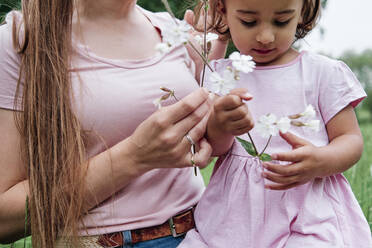 Mother and daughter holding flowers in park - ASGF00708