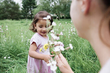 Nettes Mädchen mit Mutter hält Blumen auf Gras im Park - ASGF00710