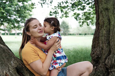 Cute girl kissing mother at park - ASGF00736