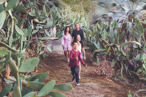Vierköpfige Familie, die fröhlich auf einem Kakteenpfad spazieren geht. - CAVF94326