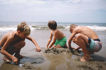 Jungen graben im Sand an einem sonnigen Sommertag - CAVF94336