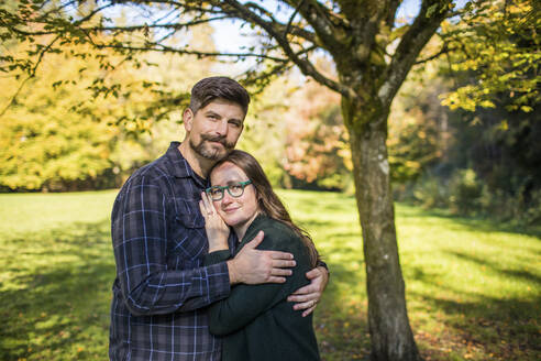 Outdoor-Porträt eines Paares im Millennial-Alter, das sich umarmt. - CAVF94358