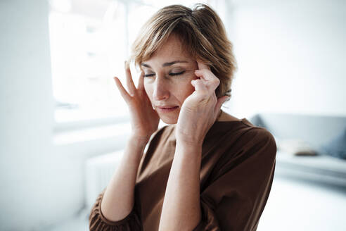 Reife Geschäftsfrau mit Kopfschmerzen im Büro - JOSEF04939