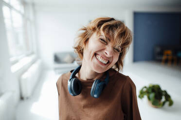Businesswoman with headphones smiling in office - JOSEF04988