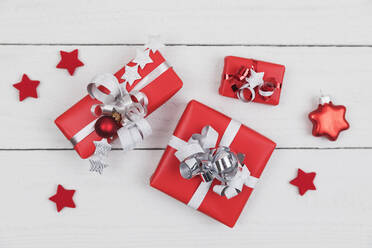 Eingepackte Geschenke und sternförmiger Weihnachtsschmuck, flach auf eine weiße Holzfläche gelegt - GWF07046