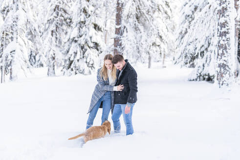 Junges Paar im Schnee stehend mit Hund im Urlaub - MEF00101