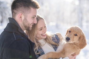 Lächelndes Paar betrachtet den Hund im Winter - MEF00109