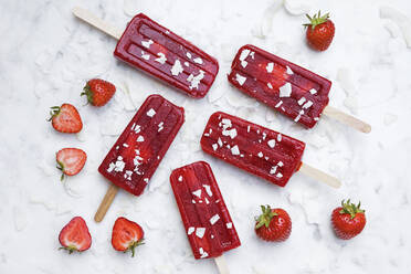 Homemade strawberry popsicles lying on marble surface - GWF07053