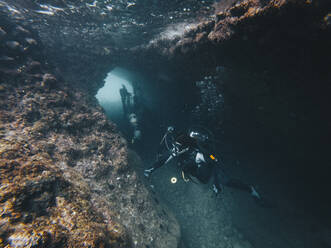 Scuba divers exploring cave undersea - RSGF00741