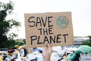 Man holding save the planet text on cardboard - JCMF02012